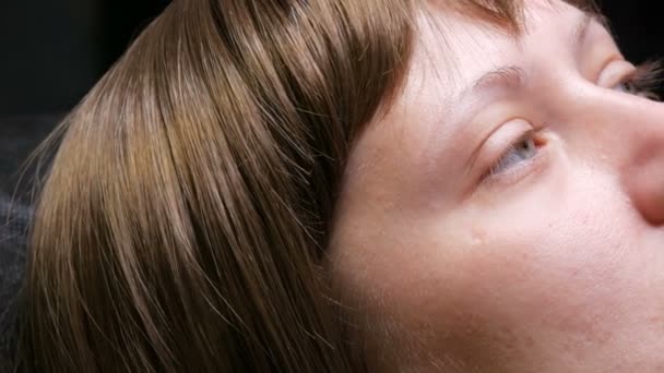 Egy fiatal nő arca kék szemekkel a kemoterápia után, aki rákos volt. Nemrég növesztett szemöldök és szempillák. Rövid paróka. - Felvétel, videó