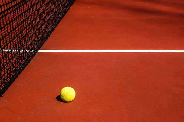 yellow tennis ball on red tennis court - Photo, Image