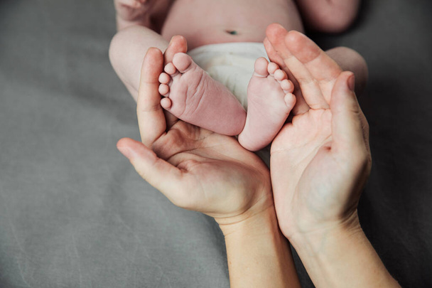 Mother holding newborn baby feet in hands. Mom taking care about infant child after taking bath. Parents childcare. Children healthcare and happy family - Photo, Image