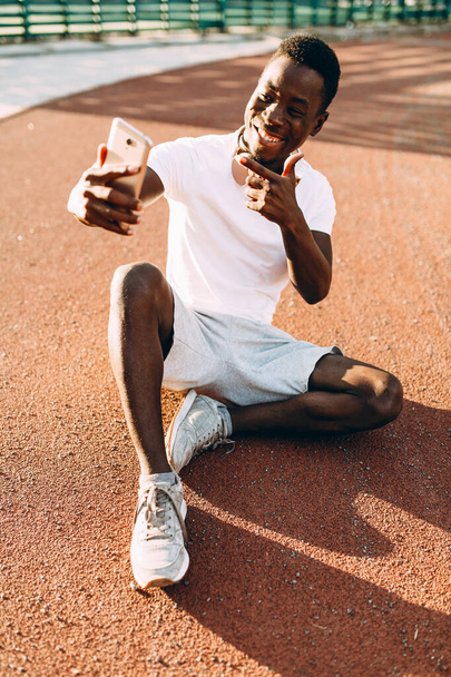 L'uomo afroamericano riposa dopo un allenamento mattutino si fa un selfie su uno smartphone
 - Foto, immagini