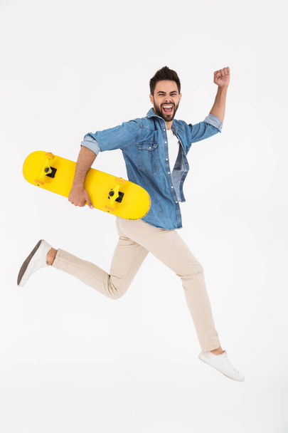 Full length image of happy excited man running and holding skateboard - Foto, Imagem