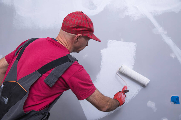 close up of male in gloves painting a wall - Photo, Image
