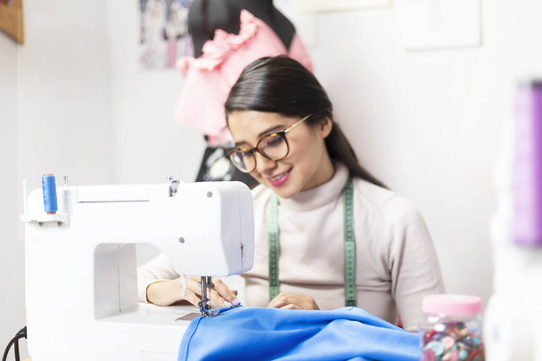 Giovane stilista che lavora felicemente sui suoi disegni con la macchina da cucire - imprenditrice creativa donna - da vicino
 - Foto, immagini
