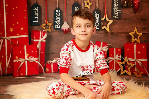 щасливий милий хлопчик 10 років на підлозі в піжамі чекає нового року і щасливого Різдва, дитинства і сім'ї
 - Фото, зображення