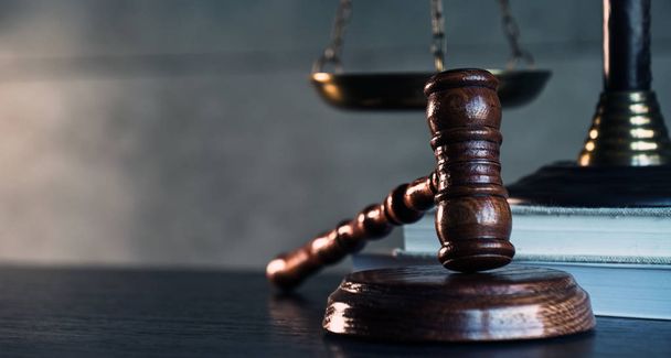 Νόμου και Δικαιοσύνης σύμβολα σε ξύλινο τραπέζι με θολή βιβλία φόντο. - Φωτογραφία, εικόνα