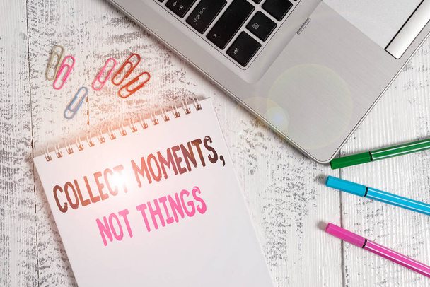Handwriting text Collect Moments Not Things. Concept meaning Happiness philosophy enjoy simple life facts Slim metallic laptop blank spiral notepad pens clips lying wooden table. - Photo, Image