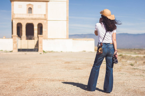 Filmmaker donna osservando una vecchia costruzione in un paesaggio desertico
 - Foto, immagini