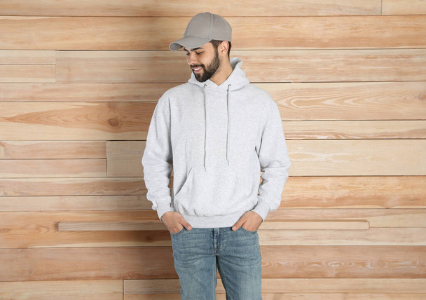 Portrait of young man in sweater at wooden wall. Mock up for design - Photo, Image