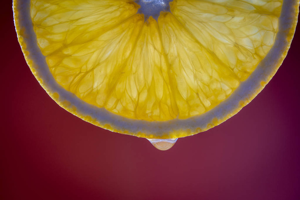 Fresh orange slice and water drop on red background, macro, closeup - Fotoğraf, Görsel