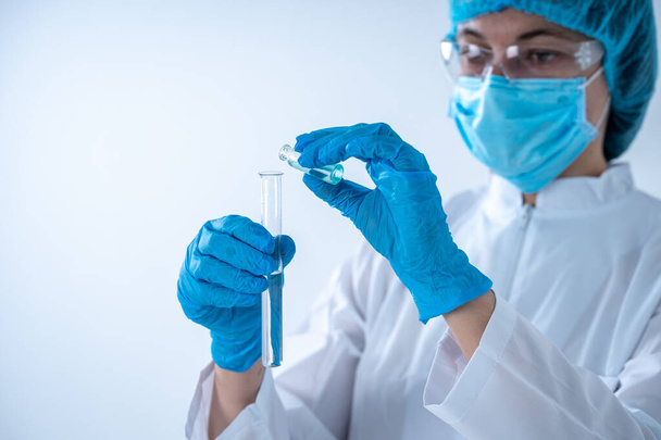 Mujer química sosteniendo tubo de ensayo con líquido, haciendo análisis de laboratorio
 - Foto, Imagen