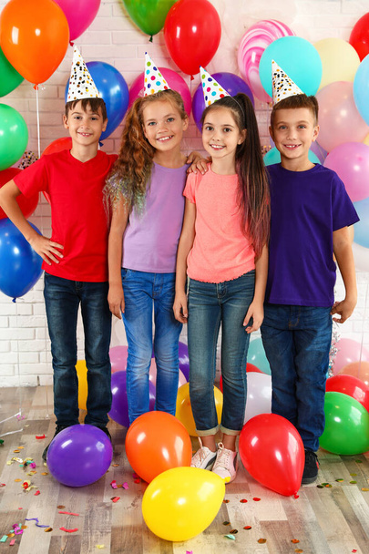 誕生日パーティーで明るい風船の近くの幸せな子供たち屋内 - 写真・画像