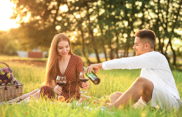 Young man and his girlfriend having picnic in green park - Fotoğraf, Görsel
