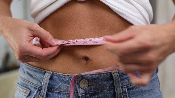 Vrolijke vrouw in jeans meet taille na afgevallen gewicht. Gewichtsverlies en dieet - Video