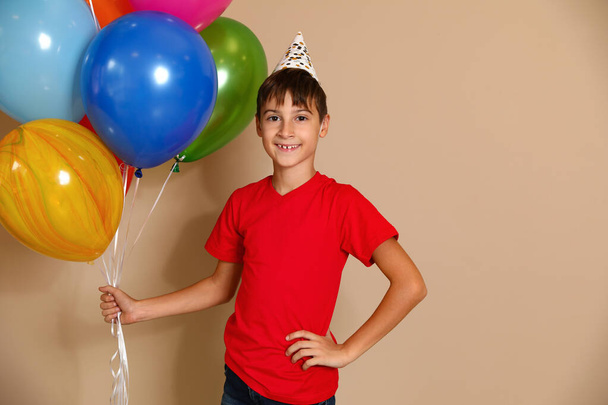 Happy boy with balloons on brown background. Birthday celebration - Foto, Bild