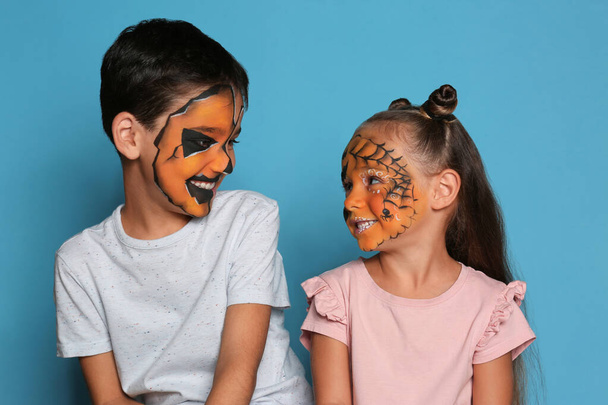 Cute little children with face painting on blue background - Foto, Imagen