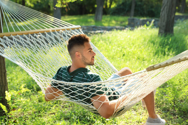 Jeune homme reposant dans un hamac confortable au jardin vert
 - Photo, image