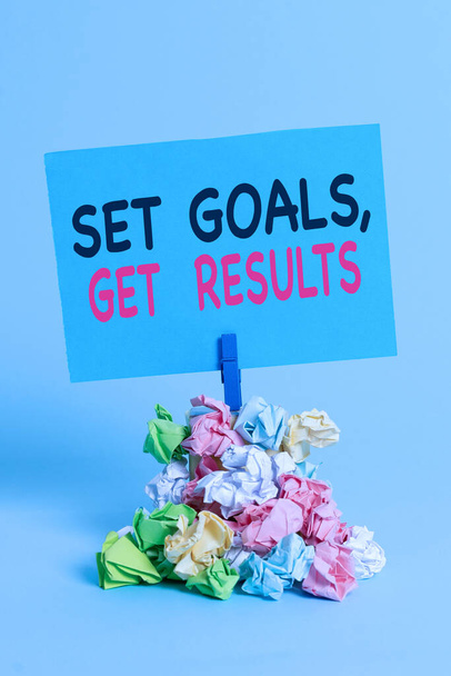 Text sign showing Set Goals Get Results. Conceptual photo Establish objectives work for accomplish them Reminder pile colored crumpled paper clothespin reminder blue background. - 写真・画像
