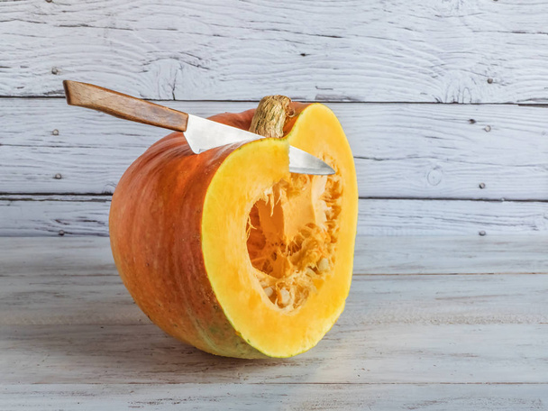 A large ripe pumpkin is cut with a knife. - Valokuva, kuva