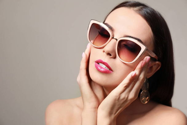 Beautiful woman in stylish sunglasses on beige background - Photo, image