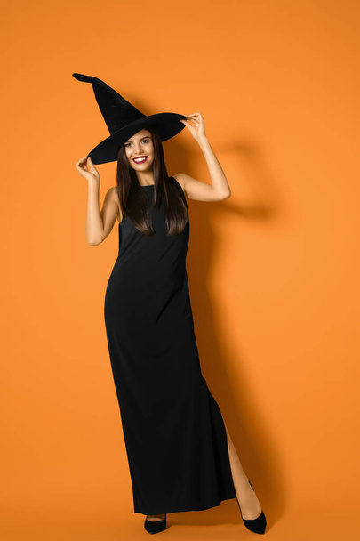 Beautiful woman wearing witch costume for Halloween party on yellow background - 写真・画像