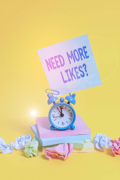 Text sign showing Need More Likes Question. Conceptual photo asking if he needs additional reaction on his post Alarm clock sticky note paper balls stacked notepads colored background. - Photo, Image
