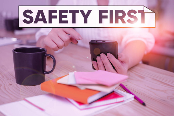 Handwriting text Safety First. Concept meaning said to mean that it is best to avoid any unnecessary risks woman using smartphone office supplies technological devices inside home. - Foto, immagini
