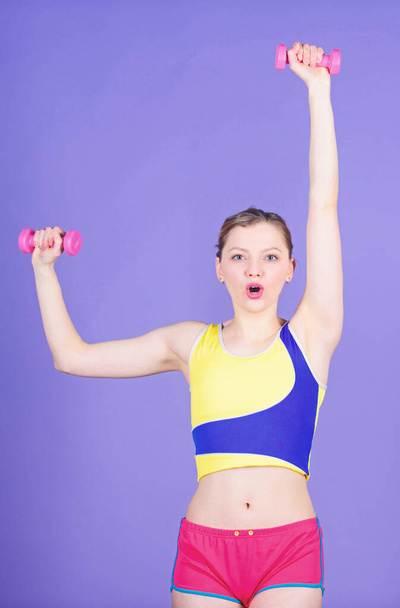 Woman exercising with dumbbells. Fitness exercises with dumbbells. Workout with dumbbells. Girl hold pink dumbbells. Biceps exercises for female. Living healthy life. Healthy lifestyle concept - 写真・画像