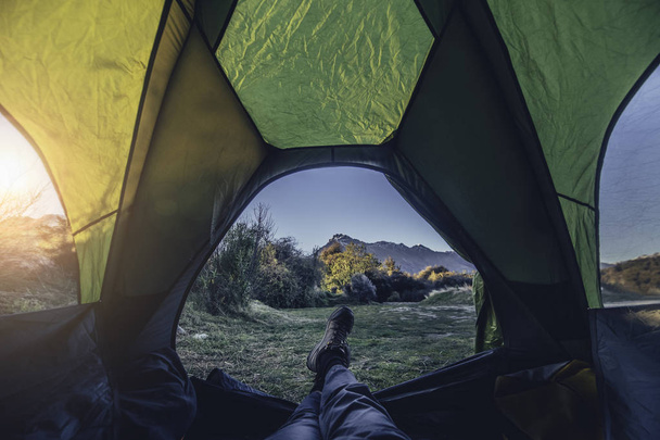 The feet of traveling man in tent camping over the lake and mountains in the morning. - Foto, afbeelding