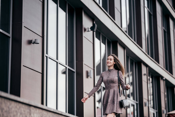 A young girl walks near the office with a handbag on her shoulder - Φωτογραφία, εικόνα
