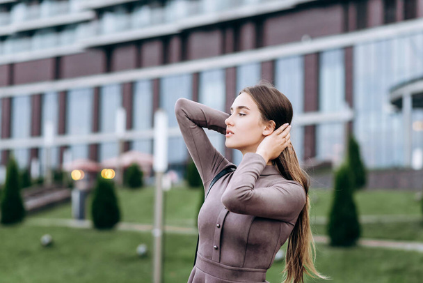 A young girl walks near the office with a handbag on her shoulder - Valokuva, kuva