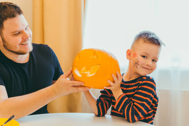 young father with toddler son making jack pumpkin head for halloween holiday - Photo, image