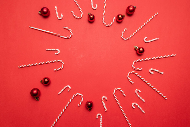Buon Natale e Buone Feste banner con cornice di palline rosse e bastoncini di zucchero su sfondo rosso. Modello modello modello biglietto di auguri disegno del testo
 - Foto, immagini