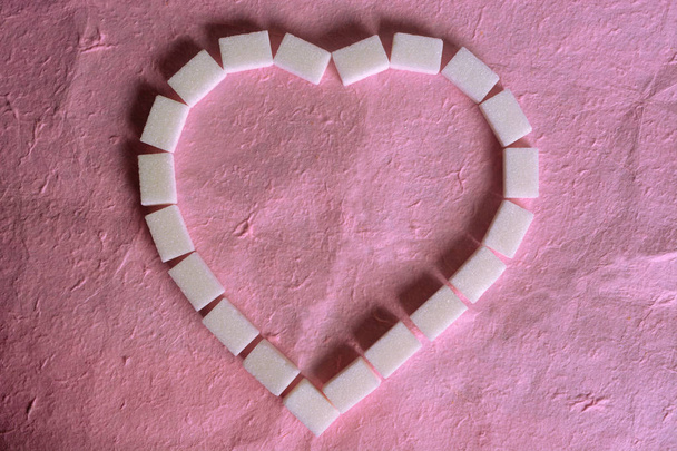 κύβους ζάχαρης σε επίπεδη γωνία lay σύρετε το σχήμα μιας καρδιάς. - Φωτογραφία, εικόνα