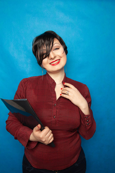 Портрет счастливой женщины в офисе, стоящей с папкой на фоне студии bluw
 - Фото, изображение