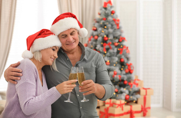 Happy mature couple with glasses of champagne at home. Christmas celebration - Foto, Imagen