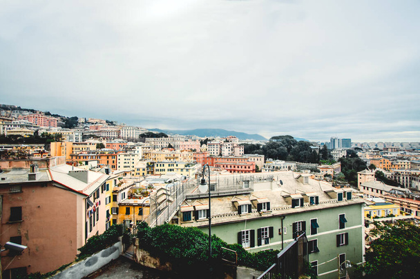 Veel mooie oude Italiaanse huizen geschilderd in felle kleuren met bergen op de achtergrond.Een verbazingwekkend stadsgezicht van een aantal sociale woningen in Genua gebouwd in de jaren '60 over heuvels van de stad in bewolkte dag, - Foto, afbeelding