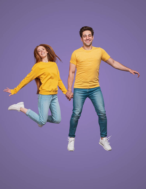 Cheerful couple jumping together and smiling - Фото, изображение