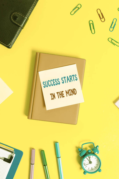 Woord schrijven tekst Succes begint in de geest. Business concept voor Hebben positieve gedachten te bereiken wat je wilt Vlak lag boven tafel met kopieerruimte paperclips klok en potloden. - Foto, afbeelding