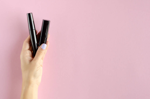 Hand with black mascara composition on pink background. - 写真・画像