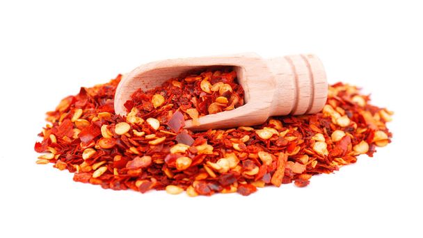 Mleté chilli a paprika v dřevěné lžíci, izolované na bílém pozadí. Směs horkého a sladkého červeného pepře se zrny. Detailní záběr. - Fotografie, Obrázek