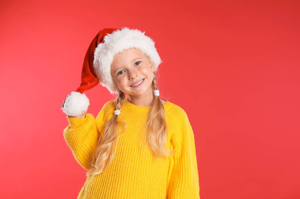 Happy little child in Santa hat on red background. Christmas celebration - Foto, imagen