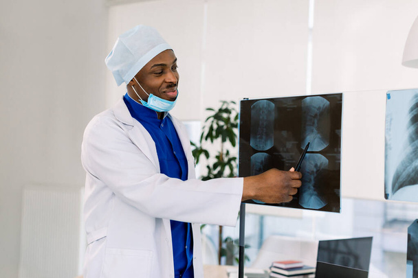 Portrait of young African male doctor surgeon or radiologist looking at a radiography - Zdjęcie, obraz