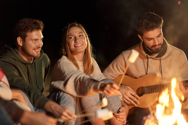 friends roasting marshmallow and playing guitar - Valokuva, kuva