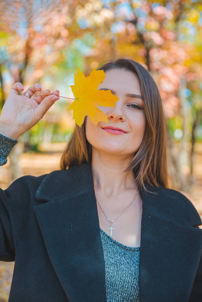 молодая красивая женщина валяет дурака с желтым кленовым листом
 - Фото, изображение