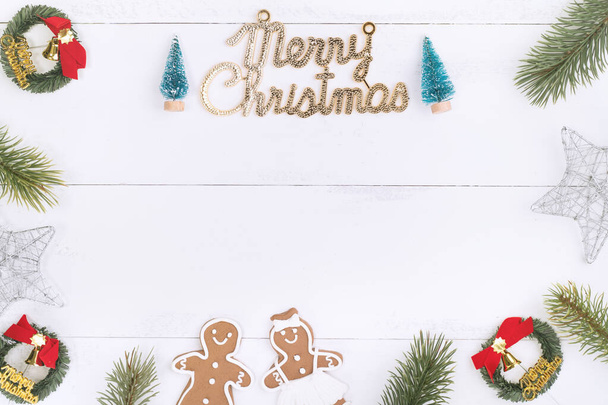Christmas concept composition decoration objects, fir tree branch wreath, gingerbread man biscuit isolated on white wooden table, top view, flat lay - Foto, imagen