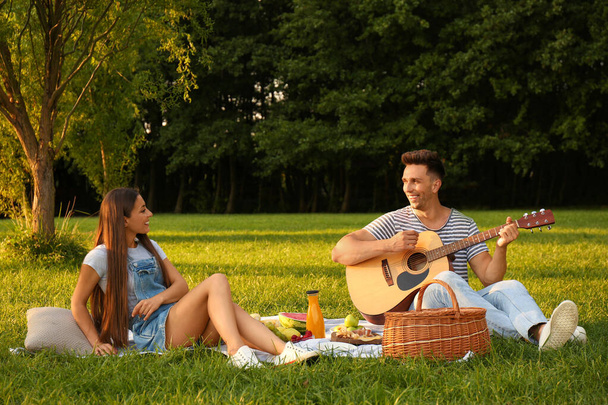 Happy couple having picnic in park on sunny day - Фото, зображення