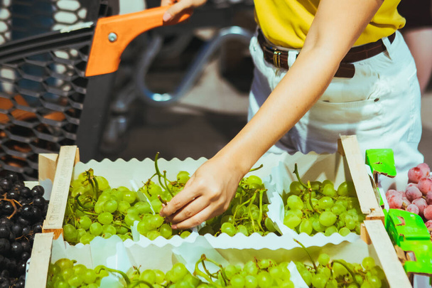 жінка рука бере виноград з коробки на ринку магазину
 - Фото, зображення