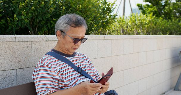 Азіатський старий користується телефоном у місті. - Фото, зображення