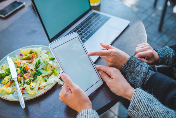 Крупный план двух женщин, встречающихся в открытом кафе, работающих на ноутбуке и планшете
 - Фото, изображение