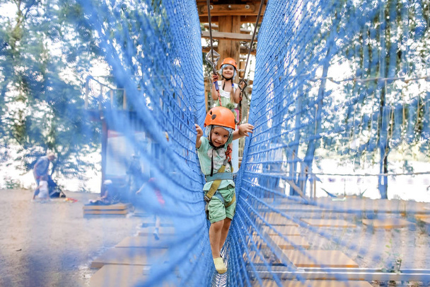 Girl and boy enjoying time in a rope structure at adventure park - Foto, afbeelding